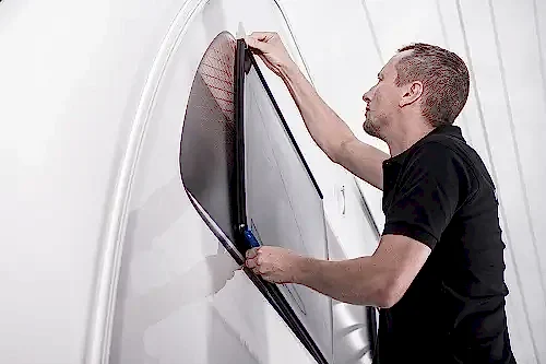 RV Weatherproofing for All Seasons | RV Masters in Kenner, LA. Image of a technician dowin window seal check of a recreational vehicle. Concept image of preventative RV maintenance services.