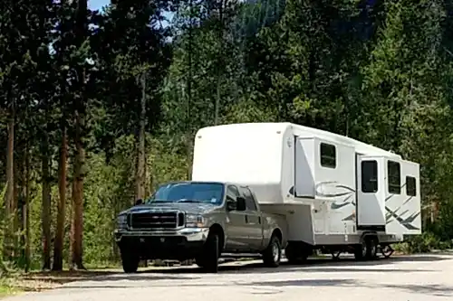 5 Maintenance Tips for Towable RVs | RV Masters in Kenner, LA. Image of a 5th wheel being towed by a light-duty truck.Concept image of towable RV services.